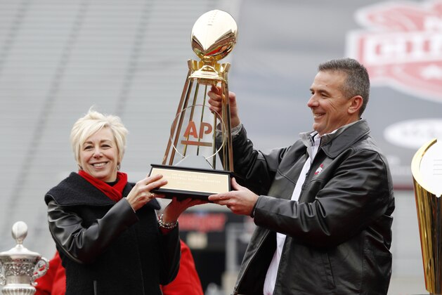 Ohio State football coach Urban Meyer, right, and The Associated Press' east regional director Eva Parziale hold up The Associated Press College Football National Championship trophy during a celebration for the 2014 College Football Playoff National Champion Ohio State football team at Ohio Stadium  in Columbus, Ohio, Saturday, Jan. 24, 2015. (AP Photo/Paul Vernon)