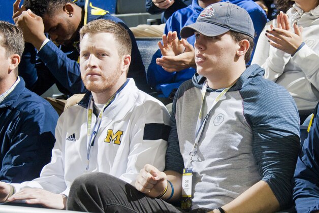 Michigan tight end coach Jay Harbaugh, left, sit with recruit Chris Clark, right, at an NCAA college basketball game against Northwestern at Crisler Center in Ann Arbor, Mich., Saturday, Jan. 17, 2015. (AP Photo/Tony Ding)