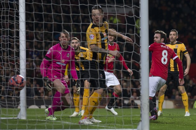 Manchester United's Juan Mata, second right, scores during the English FA Cup fourth-round replay soccer match between Manchester United and Cambridge at Old Trafford Stadium, Manchester, England, Tuesday Feb. 3, 2015. (AP Photo/Jon Super)