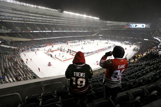 Two Chicago Blackhawks fans look out over the ice before an NHL Stadium Series hockey game between the Blackhawks and the Pittsburgh Penguins at Soldier Field on Saturday, March 1, 2014, in Chicago. (AP Photo/Charles Rex Arbogast)