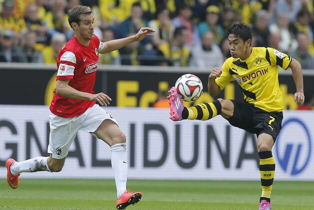 Dortmund’s Shinji Kagawa from Japan, right, and Freiburg's Julian Schuster challenge for the ball during the German first division Bundesliga soccer match between BvB Borussia Dortmund  and SC Freiburg in Dortmund, Germany, Saturday, Sept. 13, 2014. (AP Photo/Frank Augstein)