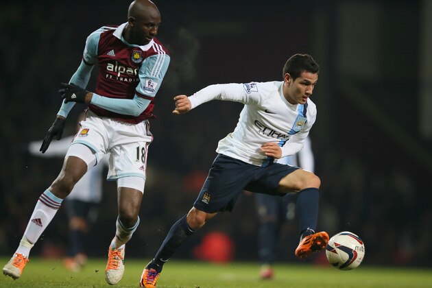 West Ham's Alou Diarra,  left, watches as Manchester City's Marcos Lopes controls the ball during the second leg of the English League Cup semifinal soccer match between West Ham United and Manchester City at the Bolyen Ground stadium in London, Tuesday, Jan. 21, 2014.(AP Photo/Alastair Grant)
