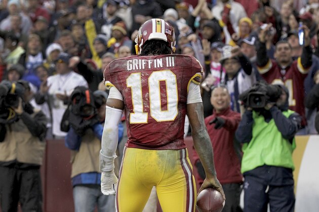 Washington Redskins quarterback Robert Griffin III (10) looks back at the crowd after scoring a touchdown on a keeper during the second half of an NFL football game against the Dallas Cowboys in Landover, Md., Sunday, Dec. 28, 2014. (AP Photo/Mark Tenally)