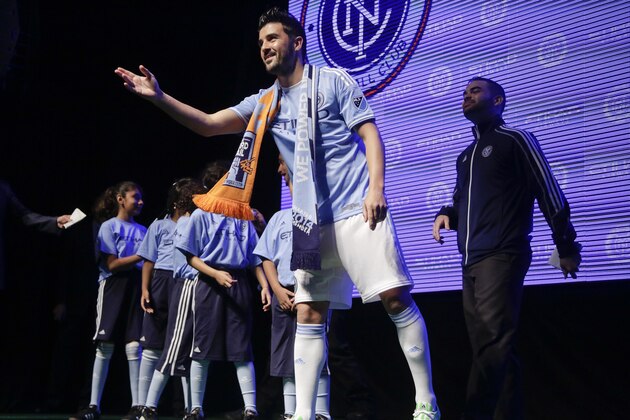 Spanish soccer star David Villa tosses team memorabilia to soccer fans while wearing the jersey to be worn by players in Major League Soccer's new team, New York City Football Club, during an introductory celebration,  Thursday, Nov. 13, 2014, in New York. New York City FC will play its first game at Yankee Stadium in March. (AP Photo/Julie Jacobson)