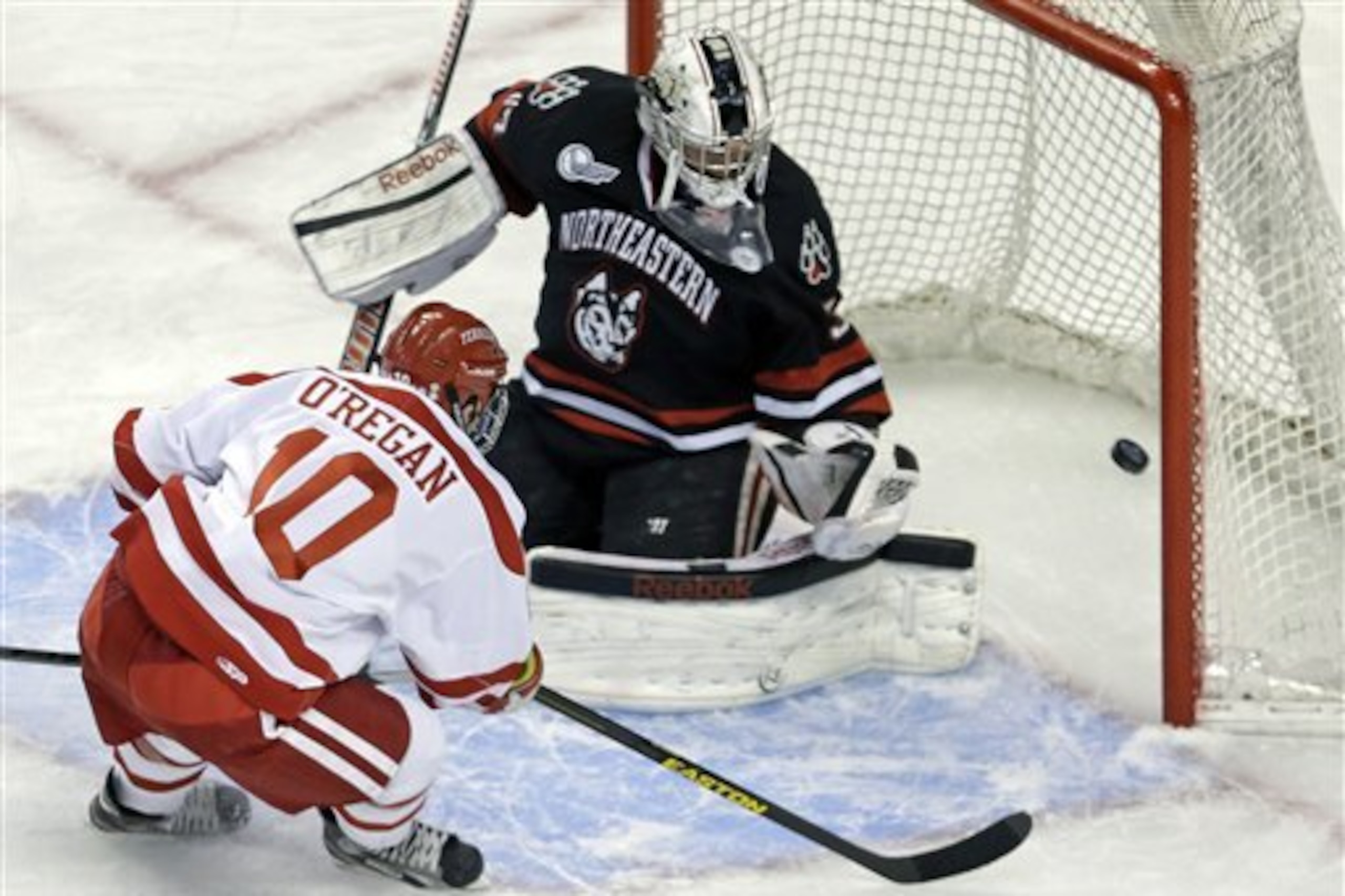 Boston forward Danny O'Regan (10) pokes the puck past Northeastern goalie Chris Rawlings for a goal during the first period of the opening round of the Beanpot college hockey tournament in Boston, Monday, Feb. 4, 2013. (AP Photo/Charles Krupa)