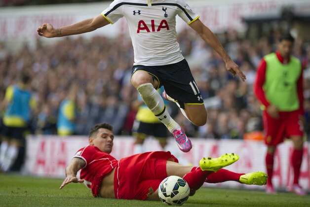 Tottenham Hotspur's Erik Lamela, top, vies for the ball with Liverpool's Dejan Lovren during their English Premier League soccer match at White Hart Lane, London, Sunday, Aug. 31, 2014 (AP Photo/Bogdan Maran)