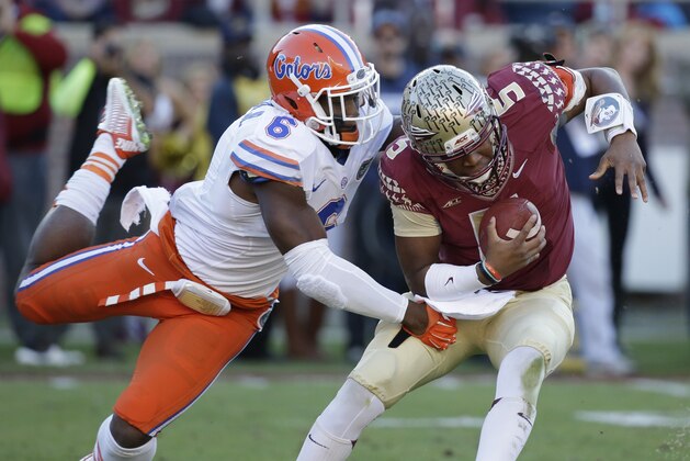 Florida State quarterback Jameis Winston (5) manages to escape a sack as he is hit by Florida defensive lineman Dante Fowler, Jr. (6) during the first half of an NCAA college football game in Tallahassee, Fla., Saturday, Nov. 29, 2014. (AP Photo/John Raoux)
