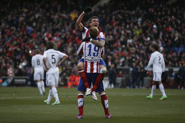Atletico's Mario Mandzukic, top, celebrates his goal with teammate Fernando Torres, bottom, during a Spanish La Liga soccer match between Atletico Madrid and Real Madrid at the Vicente Calderon stadium in Madrid, Spain, Saturday, Feb. 7, 2015. (AP Photo/Andres Kudacki)