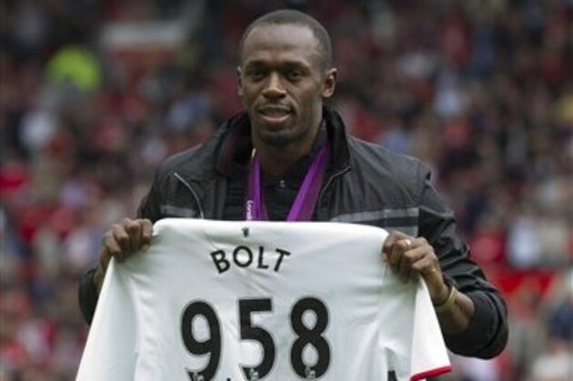 Sprinter Usain Bolt poses for pictures with a shirt showing the World Record time for the 100 metres sprint, before Manchester United's English Premier League soccer match against Fulham at Old Trafford Stadium, Manchester, England, Saturday, Aug. 25, 2012. (AP Photo/Jon Super)