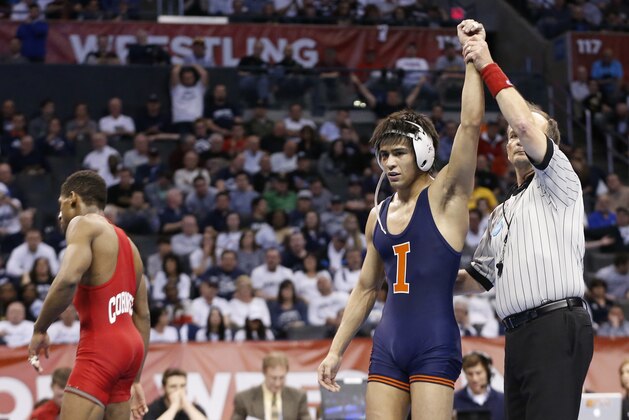 Illinois' Jesse Delgado raises his arm in victory after defeating Cornell's Nahshon Garrett, left, in the 125-pound match in the finals of the NCAA Division I wrestling championships in Oklahoma City, Saturday, March 22, 2014. (AP Photo/Sue Ogrocki)