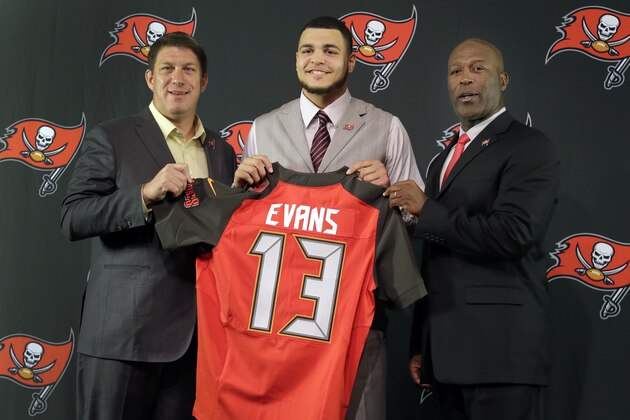 Tampa Bay Buccaneers first-round draft pick Mike Evans, center, holds up his jersey with general manager Jason Licht, left, and head coach Lovie Smith, right, after an NFL football news conference Friday, May 9, 2014, in Tampa, Fla.  Evans, a wide receiver from Texas A&M, was selected seventh overall in Thursday's draft. (AP Photo/Chris O'Meara)