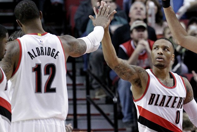 Portland Trail Blazers guard Damian Lillard, right, high-fives teammate LaMarcus Aldridge after scoring during the second half of an NBA basketball game against the Utah Jazz in Portland, Ore., Tuesday, Feb. 3, 2015.  Lillard scored 25 points while Aldridge had 22 as the Blazers defeated the Jazz 103-102. (AP Photo/Don Ryan)