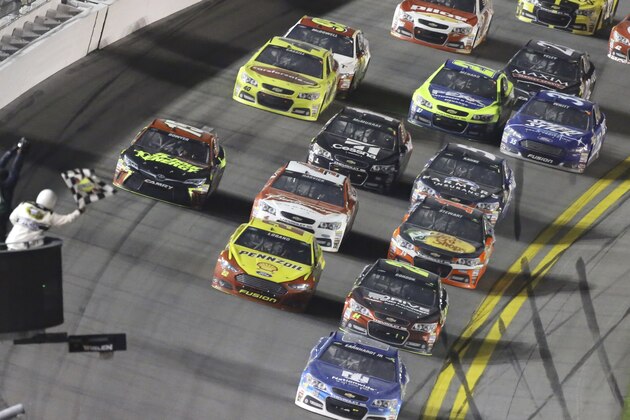 Dale Earnhardt Jr, front, takes the checkered flag to win the first of two qualifying races for the Daytona 500 NASCAR Sprint Cup series auto race at Daytona International Speedway in Daytona Beach, Fla., Thursday, Feb. 19, 2015. (AP Photo/David Graham)
