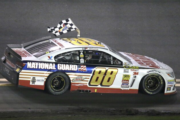 Dale Earnhardt Jr. drives in front of fans in the grandstands waving the checkered flag after winning the Daytona 500 NASCAR Sprint Cup Series auto race at Daytona International Speedway in Daytona Beach, Fla., Sunday, Feb. 23, 2014. (AP Photo/John Raoux)