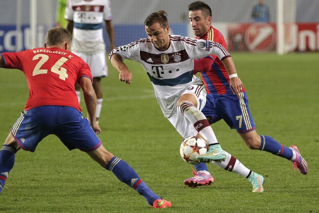 Bayern's Mario Goetze, center, passes in between CSKA's Vasili Berezutski, left, and CSKA's Zoran Tosic, right, during the Group E Champions League match between CSKA Moscow and Bayern Munich at Arena Khimki stadium in Moscow, Russia, Tuesday Sept. 30, 2014. (AP Photo/Pavel Golovkin)