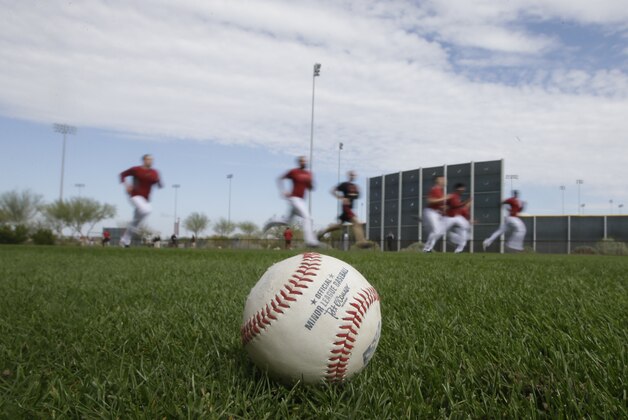A baseball is seen as Arizona Diamondbacks players run during spring training baseball practice Sunday, Feb. 22, 2015, in Scottsdale, Ariz. (AP Photo/Darron Cummings)