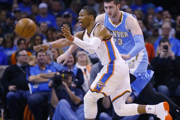 Oklahoma City Thunder guard Russell Westbrook, left, passes off to a teammate in front of Denver Nuggets center Jusuf Nurkic (23) in the second quarter of an NBA basketball game in Oklahoma City, Sunday, Feb. 22, 2015. Oklahoma City won 119-94. (AP Photo/Sue Ogrocki)
