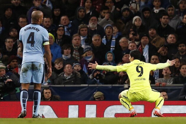 Barcelona's Luis Suarez, right, celebrates after scoring the second goal of his team as Manchester City's Vincent Kompany reacts during the Champions League Round of 16 soccer match between Manchester City and Barcelona at Etihad Stadium in Manchester, England, Tuesday, Feb. 24, 2015. (AP Photo/Jon Super)