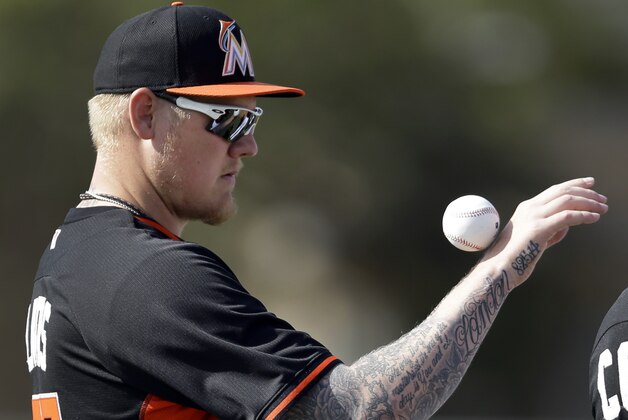 Miami Marlins pitcher Mat Latos rolls a ball down his arm while waiting to take part in a drill during spring training baseball practice Sunday, Feb. 22, 2015, in Jupiter, Fla. (AP Photo/Jeff Roberson)