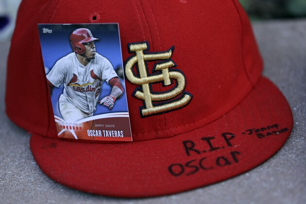A baseball card showing St. Louis Cardinals' Oscar Taveras is attached to a hat as part of a makeshift memorial outside Busch Stadium Monday, Oct. 27, 2014, in St. Louis. Taveras, the Cardinals' outfielder regarded as one of the majors' top prospects, died Sunday in a car accident in his native Dominican Republic. He was 22. (AP Photo/Jeff Roberson)