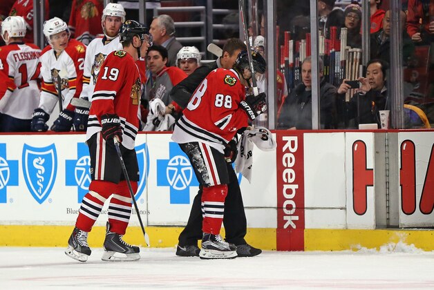 CHICAGO, IL - FEBRUARY 24: Patrick Kane #88 of the Chicago Blackhawks is helped off the ice in front of Jonathan Toews #19 after being cross-checked against the Florida Panthers at the United Center on February 24, 2015 in Chicago, Illinois.  (Photo by Jonathan Daniel/Getty Images)