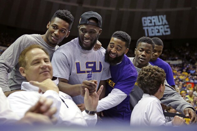 Current members of the LSU football team greet head coach Les Miles, left, in the second half of an NCAA college basketball game between LSU and Kentucky in Baton Rouge, La., Tuesday, Feb. 10, 2015.  Kentucky won 71-69. (AP Photo/Gerald Herbert)