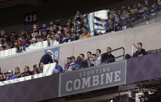 Fans watch as players run through drills at the NFL football scouting combine in Indianapolis, Saturday, Feb. 21, 2015. (AP Photo/David J. Phillip)