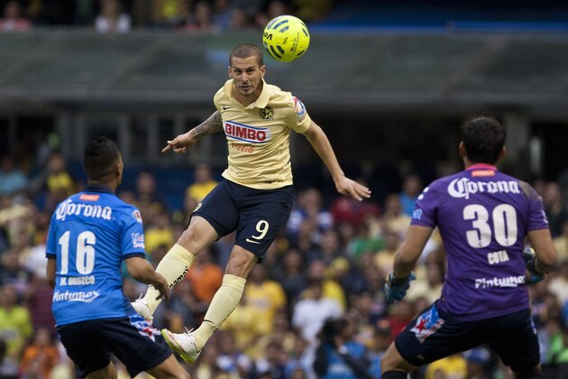 America's Dario Bendetto heads the ball against the defense of Puebla goalkeeper Rodolfo Cota, right and Michael Orozco, during a Mexican soccer league match in Mexico City, Saturday, Jan. 24, 2015. (AP Photo/Christian Palma)
