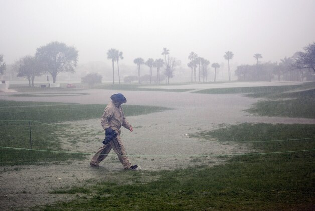 A photographer makes his way across a flooded 10th hole as rain postponed the third round of the Honda Classic golf tournament, Saturday, Feb. 28, 2015 in Palm Beach Gardens, Fla. Play will resume Sunday morning. (AP/J Pat Carter)