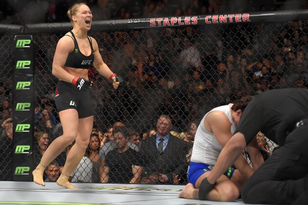 Ronda Rousey, left, celebrates as Cat Zingano kneels on the mat during a UFC 184 mixed martial arts bantamweight title bout, Saturday, Feb. 28, 2015, in Los Angeles. Rousey won after Zingano tapped out 14 seconds into the bout. (AP Photo/Mark J. Terrill)