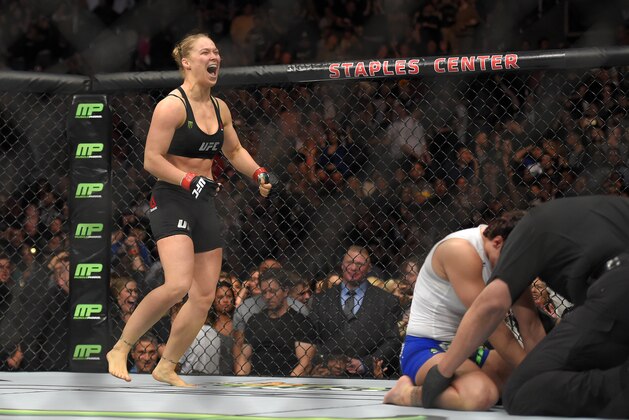 Ronda Rousey, left, celebrates as Cat Zingano kneels on the mat during a UFC 184 mixed martial arts bantamweight title bout, Saturday, Feb. 28, 2015, in Los Angeles. Rousey won after Zingano tapped out 14 seconds into the bout. (AP Photo/Mark J. Terrill)