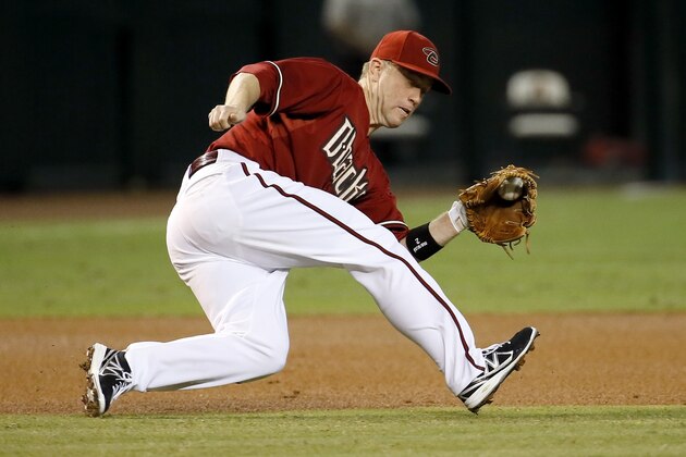 Arizona Diamondbacks' Aaron Hill stops a ground ball hit by San Francisco Giants Gregor Blanco during the first inning of a baseball game, Wednesday, Sept. 17, 2014, in Phoenix. (AP Photo/Matt York)