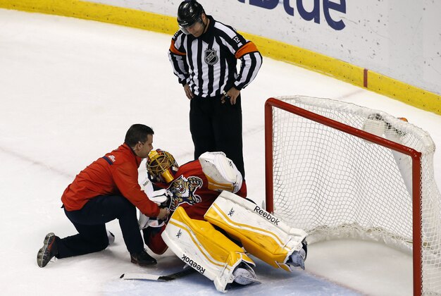 Mar 3, 2015; Sunrise, FL, USA; Florida Panthers trainer David Zenobi attends to injured goalie Roberto Luongo as referee  Justin St. Pierre looks on in the first period at BB&T Center. Mandatory Credit: Robert Mayer-USA TODAY Sports