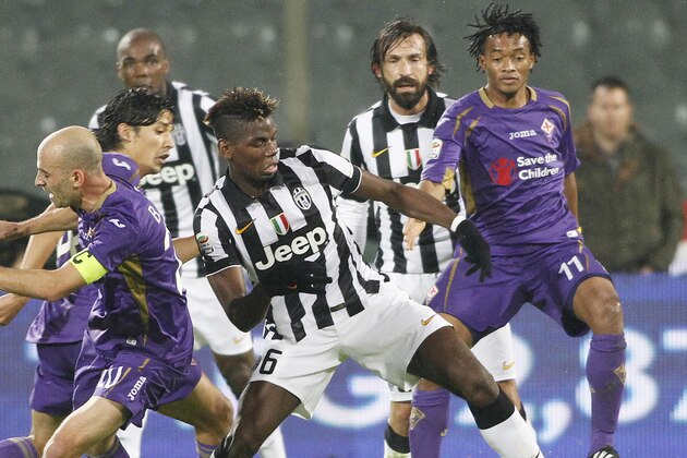 Fiorentina's Stefan Savic, left, is challenged by Juventus' Paul Pogba, center, during a Serie A soccer match at the Artemio Franchi stadium in Florence, Italy , Friday Dec. 5  2014. In background right is Fiorentina's Cuadrado. (AP Photo/Fabrizio Giovannozzi)