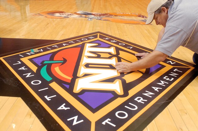 Ira Blackburn, an employee of Sports Unlimited, works on the newly placed NIT logo prior to an NCAA college basketball game in Stillwater, Okla., Tuesday, Mar. 13, 2007.  Oklahoma State takes on Marist in the first round of play Tuesday evening. (AP Photo/Brody Schmidt)