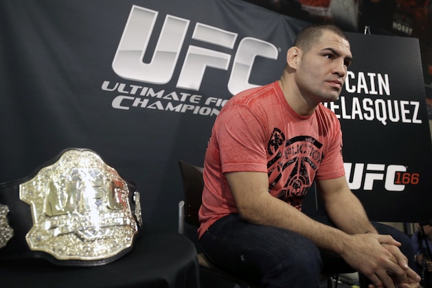 Sitting beside his championship belt, UFC heavyweight champion Cain Velasquez answers questions during a media availability Thursday, Oct. 17, 2013, in Houston. Velasquez will face former UFC heavyweight champion Junior Dos Santos in a rematch in Houston Saturday. He beat Santos in a five-round decision in December to regain the title after Santos won in a knockout in the first meeting in 2011. (AP Photo/Pat Sullivan)