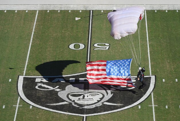 November 9, 2014; Oakland, CA, USA; A man parachutes over the midfield logo before the game between the Denver Broncos and the Oakland Raiders at O.co Coliseum. The Broncos defeated the Raiders 41-17. Mandatory Credit: Kyle Terada-USA TODAY Sports