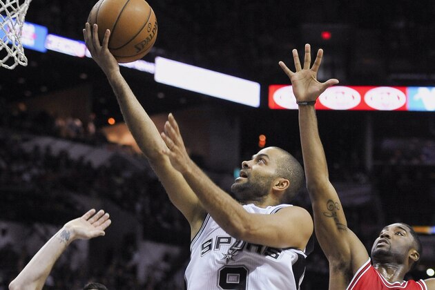 El base de los Spurs de San Antonio, Tony Parker, dispara ante la marca de los escoltas de los Toros de Chicago, Kirk Hinrich y E'Twan Moore durante la primera mitad del juego de NBA del domingo 8 de marzo de 2015 en San Antonio, Texas. (Foto AP/Darren Abate).