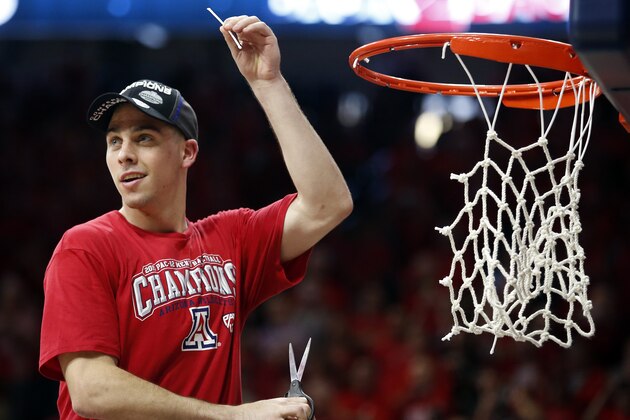 Arizona guard T.J. McConnell cuts down part of the net after defeating Stanford 91-69 and winning the Pac-12 conference after an NCAA college basketball game, Saturday, March 7, 2015, in Tucson, Ariz. (AP Photo/Rick Scuteri)