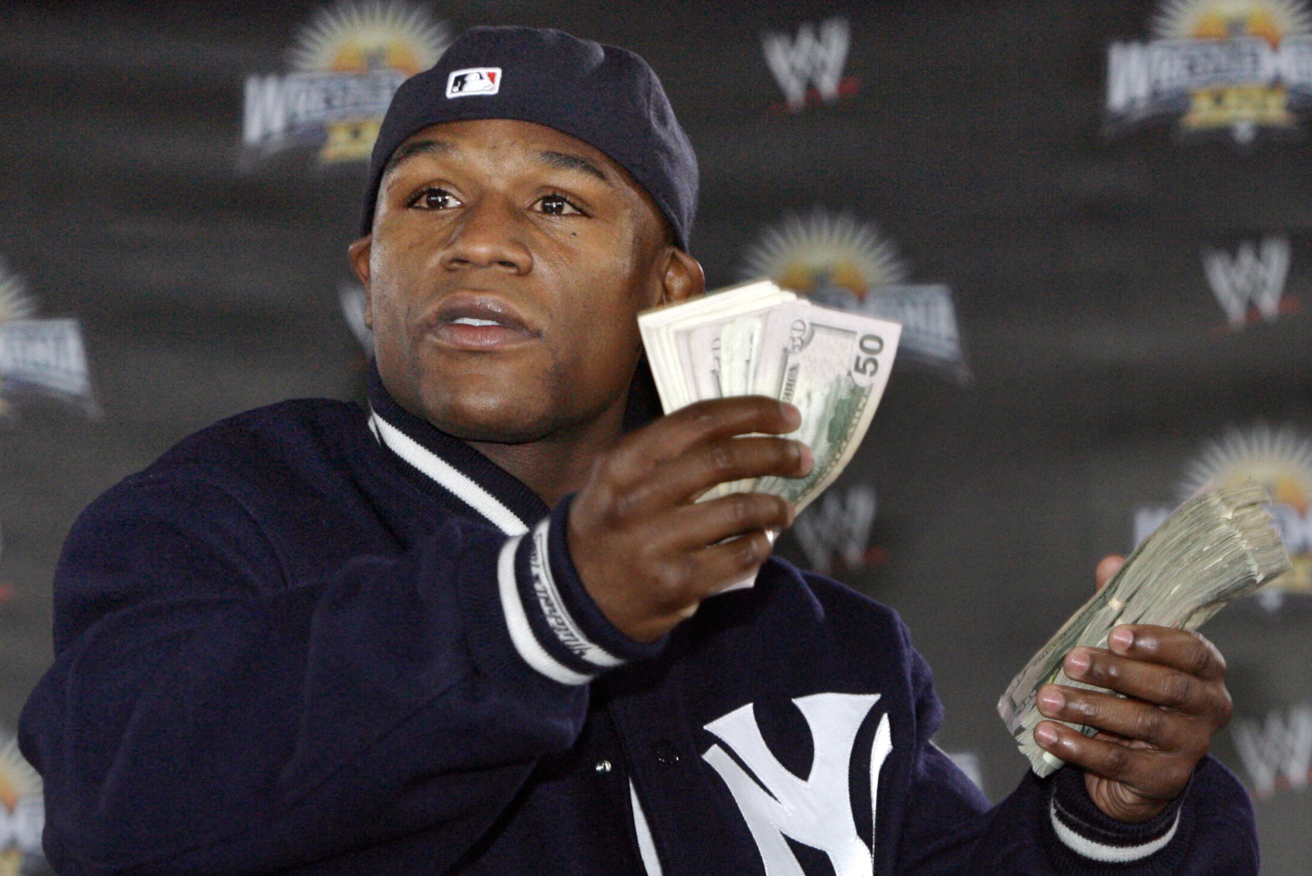 Champion boxer Floyd Mayweather tosses a roll of dollars to fans at a news conference at the Staples Center in Los Angeles Monday, Feb 25, 2008. Mayweather is preparing wrestle as part of WWE's Champion boxer Floyd Mayweather tosses a roll of dollars to fans at a news conference at the Staples Center in Los Angeles Monday, Feb 25, 2008. Mayweather is preparing wrestle as part of WWE's