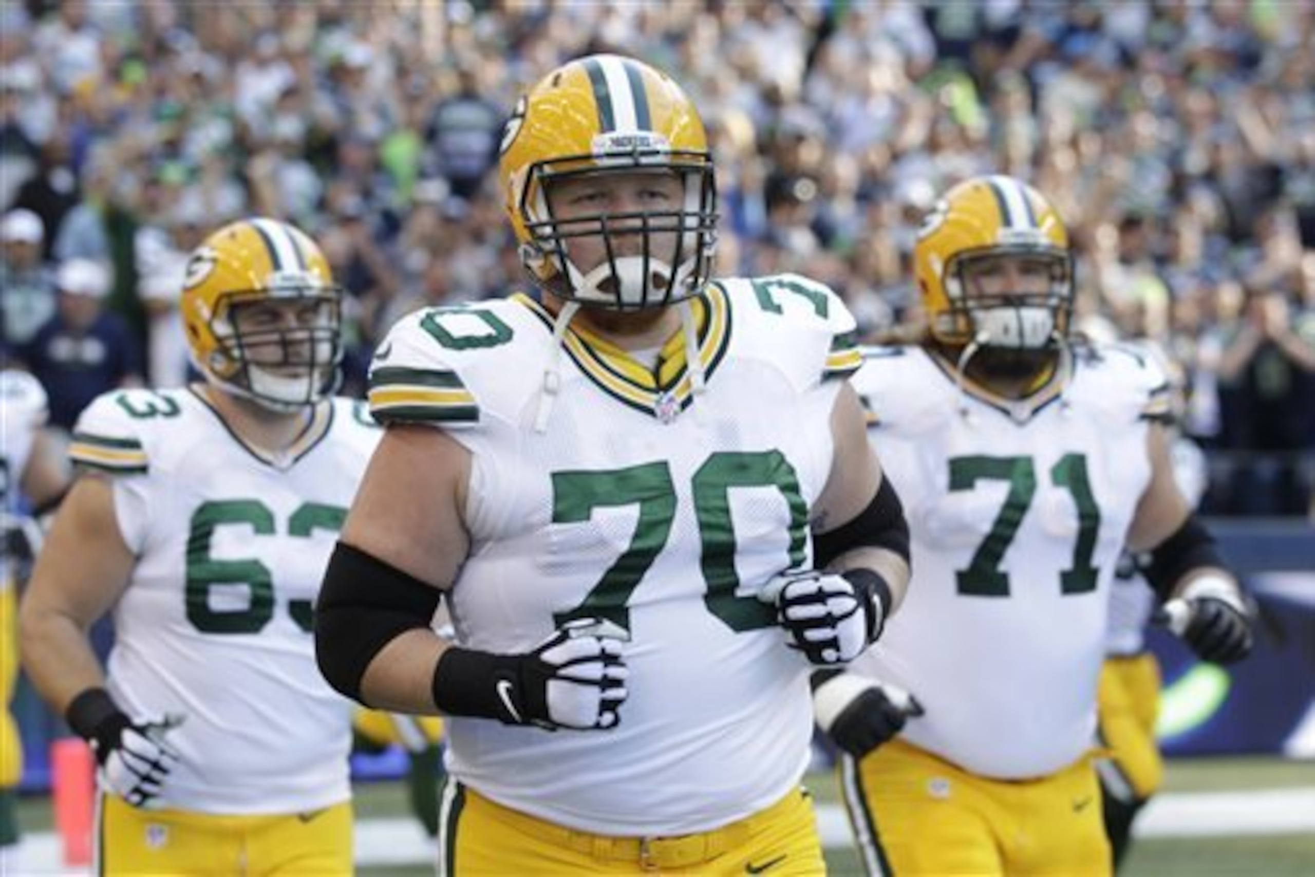 FILE - In this Sept. 4, 2014, file photo, Green Bay Packers guard T.J. Lang (70),  center Corey Linsley, left, and guard Josh Sitton take the field before an NFL football game against the Seattle Seahawks in Seattle. The Packers can't be prolific with quarterback Aaron Rodgers on the ground. The offensive line has been keeping Rodgers clean and upright lately. (AP Photo/Stephen Brashear, File)