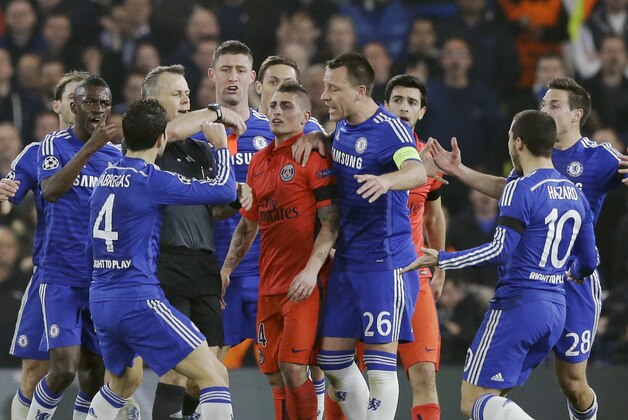 In this photograph taken Wednesday, March 11, 2015, Chelsea players remonstrate with referee Bjorn Kuipers as he holds his red card before showing it to PSG's Zlatan Ibrahimovic during the Champions League round of 16 second leg soccer match between Chelsea and Paris Saint Germain at Stamford Bridge stadium in London.  PSG forward Zlatan Ibrahimovic was ejected in the 31st minute for a challenge on Oscar.  (AP Photo/Matt Dunham)