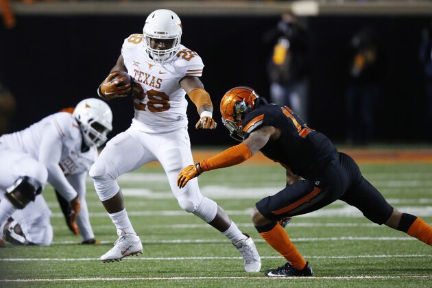 Texas's Malcolm Brown (28) tries to avoid a tackle by Oklahoma State safety Jordan Sterns (13) in the third quarter of an NCAA college football game in Stillwater, Okla., Saturday, Nov. 15, 2014. Texas won 28-7. (AP Photo/Sue Ogrocki)