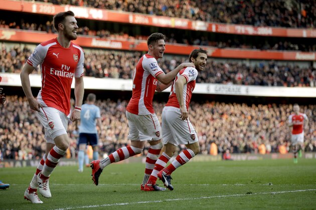 Arsenal's Mathieu Flamini, right, celebrates after scoring his side's third goal with Olivier Giroud, center, and Aaron Ramsey during the English Premier League soccer match between Arsenal and West Ham United at the Emirates Stadium in London, Saturday, March 14, 2015.  (AP Photo/Matt Dunham)