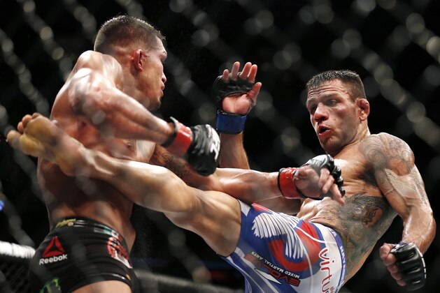 Rafael dos Anjos, right, delivers a kick to Anthony Pettis during a men's lightweight mixed martial arts title bout, Saturday night, March 14, 2015, at UFC 185 in Dallas. Rafael dos Anjos won in five rounds. (AP Photo/Brandon Wade)