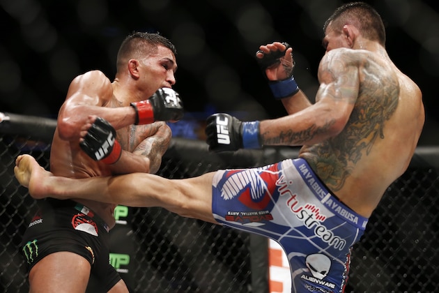 Rafael dos Anjos, right, delivers a kick to Anthony Pettis during a men's lightweight mixed martial arts title bout, at UFC 185 early Sunday, March 15, 2015, in Dallas. Rafael dos Anjos won in a unanimous decision. (AP Photo/Brandon Wade)