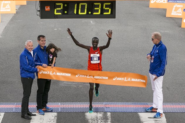 Daniel Limo, center, from Kenya, crosses the finish line to win the Los Angeles Marathon in Santa Monica, Calif., Sunday, March 15, 2015. (AP Photo/Damian Dovarganes)