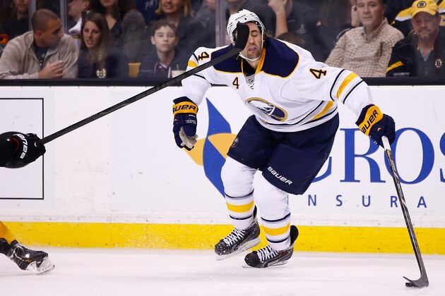 BOSTON, MA - DECEMBER 21: Jamie McBain #4 of the Buffalo Sabres takes a high stick to the face in the second period against the Boston Bruins during the game at TD Garden on December 21, 2013 in Boston, Massachusetts.  (Photo by Jared Wickerham/Getty Images)