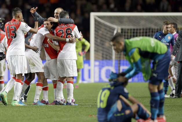 Arsenal's Santi Cazorla, 2nd right, is comforted by an unidentified teammate while Monaco celebrate after the final whistle of the Champions League round of 16 second leg soccer match between Monaco and Arsenal at Louis II stadium in Monaco, Tuesday, March 17, 2015. Monaco withstood Arsenal's onslaught to reach the quarterfinals of the Champions League despite a 2-0 home defeat on Tuesday, advancing on the away goals rule after drawing 3-3 on aggregate.  (AP Photo/Lionel Cironneau)
