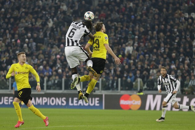 Juventus' Paul Pogba and Dortmund's Marcel Schmelzer, right, jump for the ball during the Champions League round of 16 first leg soccer match between Juventus and Borussia Dortmund at the Juventus stadium in Turin, Italy, Tuesday, Feb. 24, 2015. (AP Photo/Antonio Calanni)